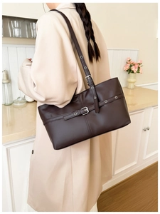 Detail of dark brown PU tote bag featuring silver buckle straps and adjustable shoulder strap