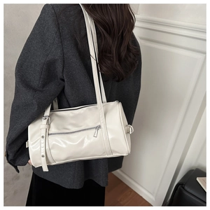 Model wearing a cream-colored Boston shoulder bag with metallic zippers and PU leather finish