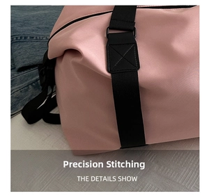 Detail of pink waterproof travel bag showing reinforced cross-stitching on black nylon strap
