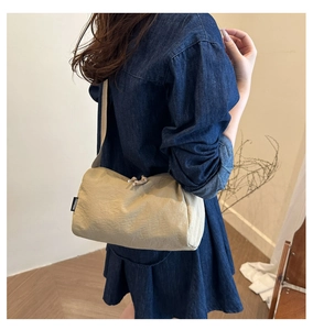 Close-up of beige knotted nylon crossbody bag worn with a stylish denim outfit