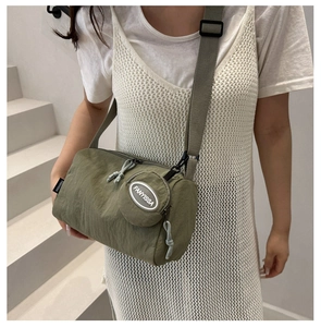 Detail of green nylon cylindrical crossbody bag with small round coin pouch attachment