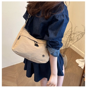 Gros plan du sac sous l'aisselle en nylon beige minimaliste avec texture plissée et logo