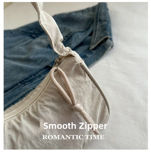 Close-up of smooth zipper with woven rope puller on beige crescent shoulder bag