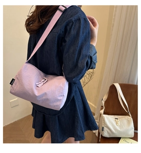 Detailed view of the purple nylon tote featuring a side brand label and adjustable strap