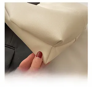 Detail shot of the precise stitching and lychee grain texture on a cream leather bag