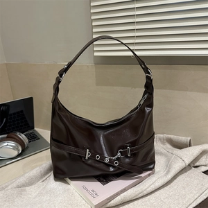 Retro dark brown underarm bag in polished finish, sleek hobo style on a lifestyle desk