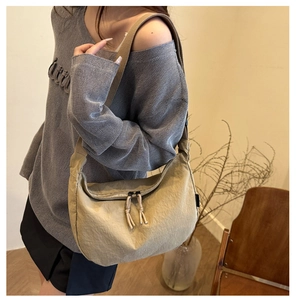 Detail of khaki crescent crossbody bag with pleated nylon texture and wide strap
