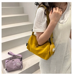 Detail of cylinder crossbody bag with adjustable strap and matching round coin purse