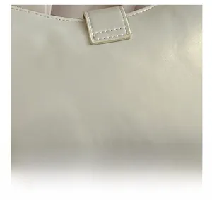 Detail shot of cream leather bag showing reinforced stitching and premium grain texture