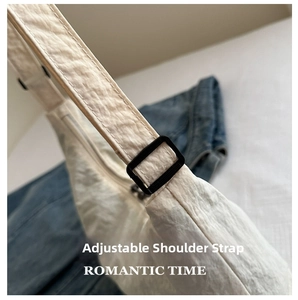 Detail of adjustable strap with black buckle and stitching on off-white nylon tote bag