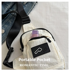 Close-up of front zipper pocket on minimalist off-white crossbody phone bag