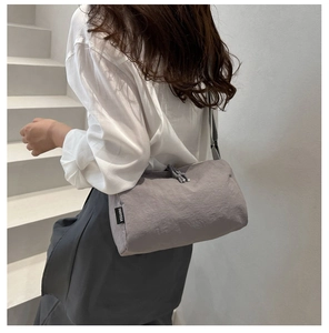 Detail view of the lilac grey nylon cylinder bag featuring a branded fabric label