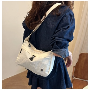 Dettaglio della borsa a tracolla in nylon bianco con trama plissettata e zip triangolare
