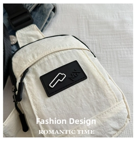 Detailed close-up of cream nylon chest bag featuring black rubberized logo and zipper