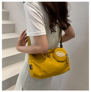 Detail view of bright yellow canvas square bag with wide strap and matching mini coin purse