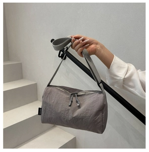 Detail of grey nylon crossbody bag showing the woven FANTISSA label and dual zippers