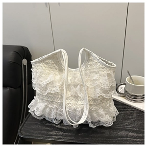 Dettaglio della borsa tote in pizzo bianco a strati su un tavolo di legno scuro