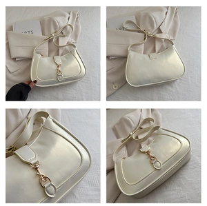 Close-up of cream-white underarm bag with gold metal buckle and smooth leather texture