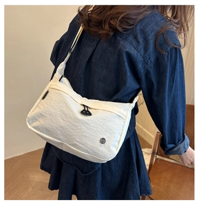 Detailed shot of white nylon crossbody bag with textured fabric worn by model