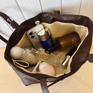 Deep brown retro tote bag showing large capacity with daily items and smooth leather texture