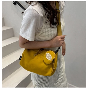 Detail showing the vibrant yellow dumpling crossbody bag featuring a matching small pouch