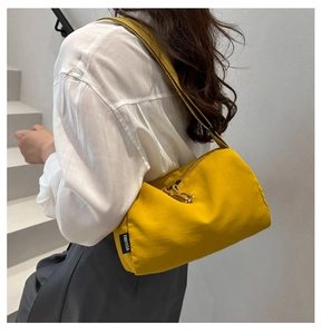Detail of yellow nylon crossbody bag with woven strap and branded label by Fanyissa