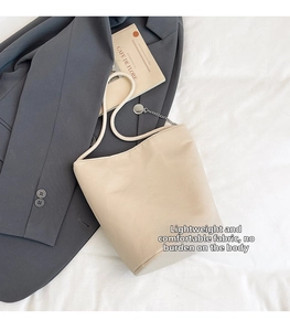 Detail view of cream bucket bag with braided rope strap and metal chain accent
