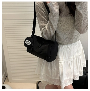 Detail of black cylinder canvas crossbody bag with adjustable strap and mini coin pouch