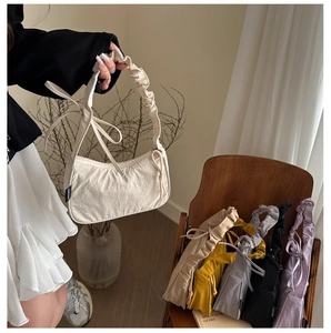 Detail of the chic nylon shoulder bag featuring a ruched strap and long ribbon accents
