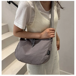 Detail of grey nylon crescent bag showing the adjustable strap and drawstring closure