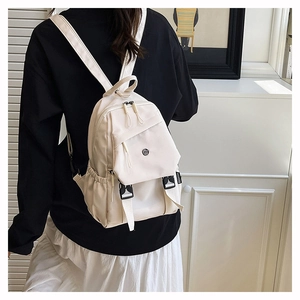 Detail of off-white lightweight nylon backpack featuring side drawstring pockets and buckle