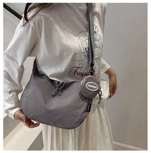 Détail de la sacoche grise minimaliste en nylon avec sangle réglable et pochette ronde