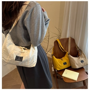 Detailed view of the crescent moon crossbody bag in beige, yellow and khaki color options