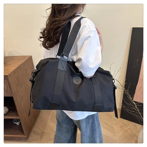 Detail of black waterproof travel bag with double handles and fashion logo patch