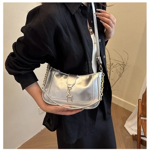 Close-up of metallic silver shoulder bag with gold hardware and chain on model