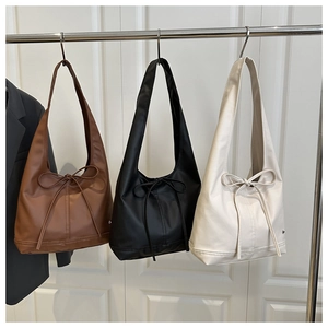 Detailansicht von drei Schultertaschen aus Ölwachsleder mit eleganten Schleifendetails.