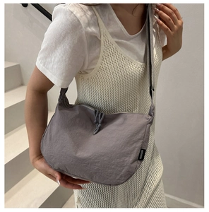 Detail of dark grey nylon crossbody bag featuring drawstring design and fabric strap