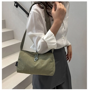 Olive green nylon shoulder bag detail showing side logo tag and textured fabric
