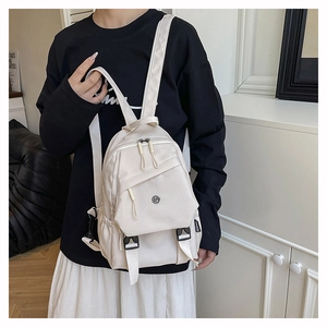 Detail view of cream white nylon backpack with multi-pocket design and buckle strap