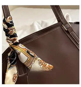 Detail of dark brown tote bag featuring contrast stitching and a patterned silk scarf