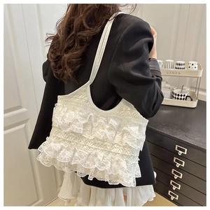 Detail of white lace tote bag with romantic layered ruffles and floral hollow textures