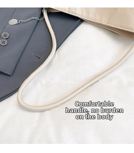Detail of beige lychee leather shoulder bag strap with silver chain and metal charm