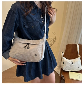 Detail of soft nylon crossbody bag with pleated texture and triangular metal zipper puller