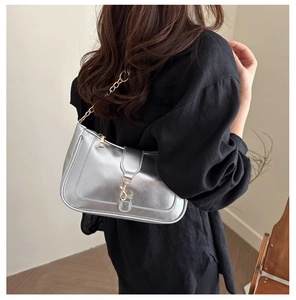 Close-up of silver leather hobo bag with gold chain strap worn over black top