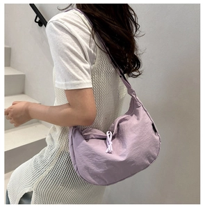 Detail of light purple nylon crescent bag featuring smooth texture and knot zipper pull