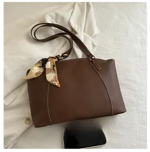 Detail of dark brown tote bag with white stitching and vintage floral silk scarf handle
