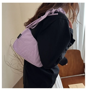 Detail of lavender nylon shoulder bag with ruffled strap design worn by a model
