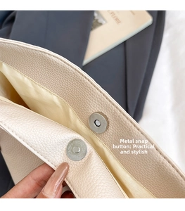 Detail of magnetic snap closure on a cream-colored pebbled leather bucket bag