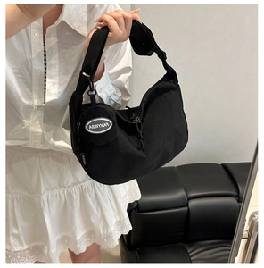 Détail du sac croissant en nylon noir avec large bandoulière et porte-monnaie rond
