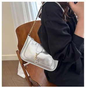Silver matte leather bag with gold chain strap and push-lock buckle worn by a model